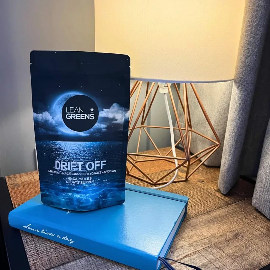 A pack of Drift Off on a bedside table beside a lamp and a book